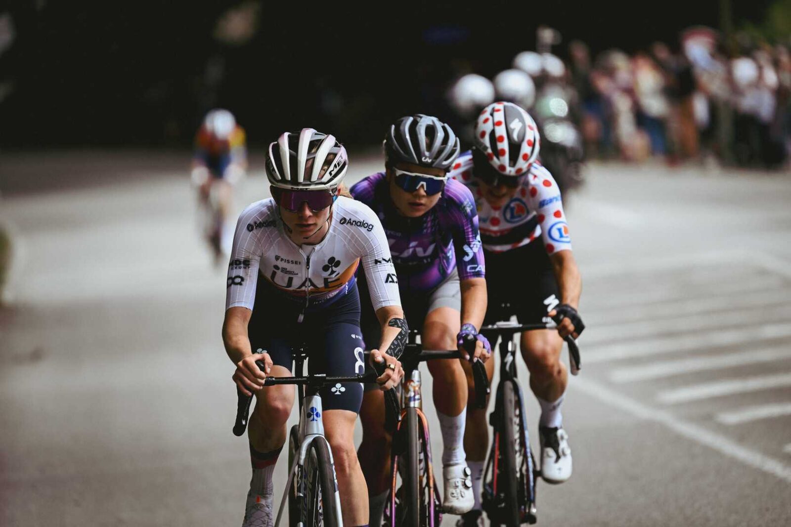 A group of cyclists racing together on an open road, riding in a tight pack during an outdoor cycling event.