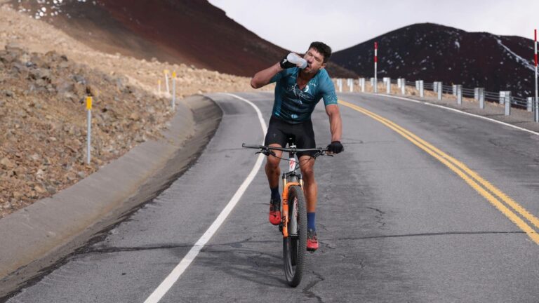 Cyclist drinking electrolytes mid-race to maintain hydration and sustain energy during endurance ride