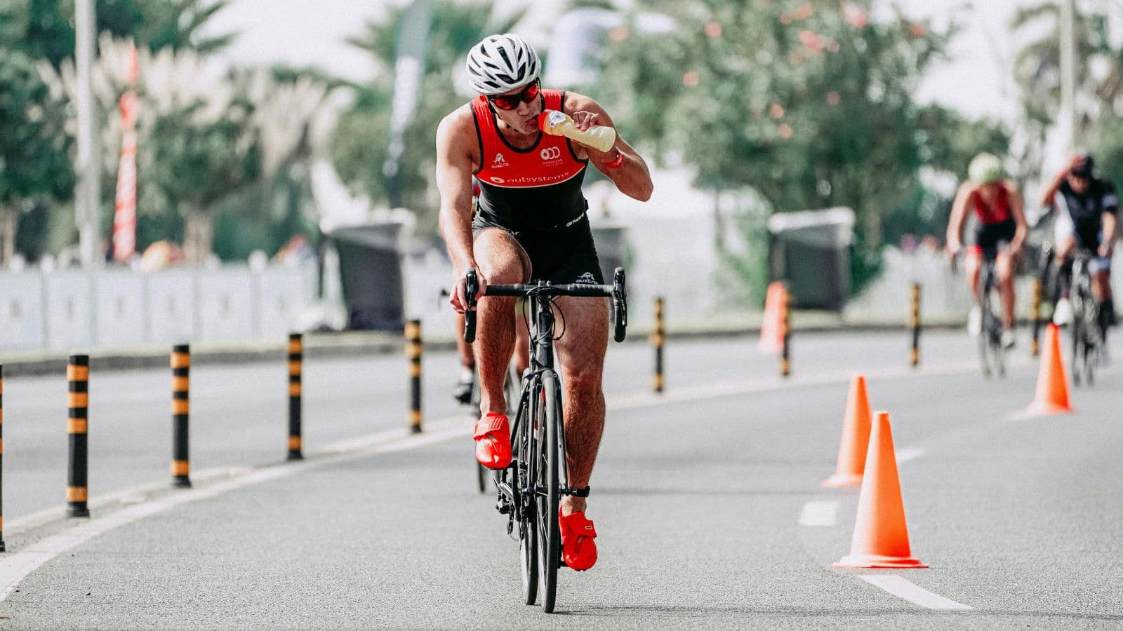 Cyclist riding during training while drinking water to maintain hydration and performance