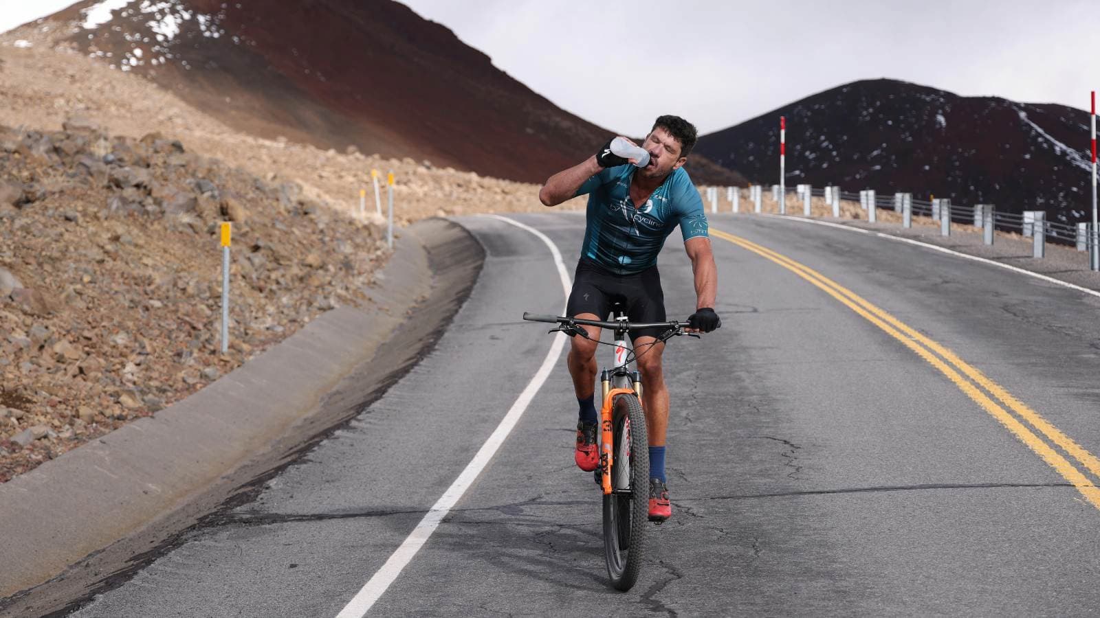 Cyclist drinking water while riding, demonstrating hydration and fueling strategies for long-distance cycling rides