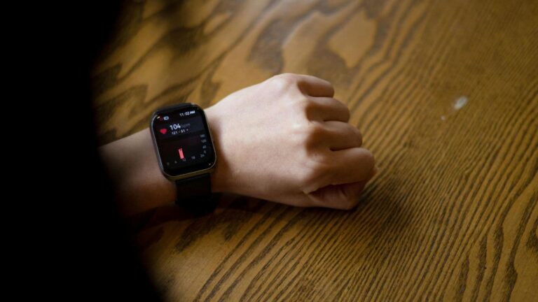 Runner checking smartwatch showing heart rate at 102 bpm during low-intensity Zone 2 training