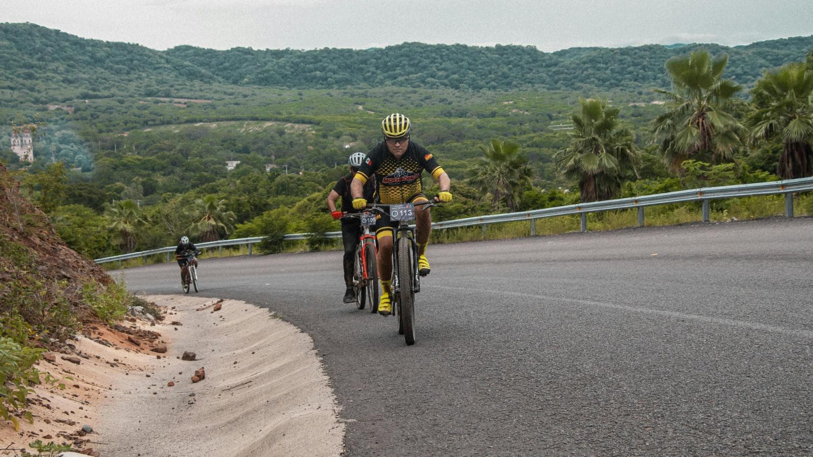 Beginner cyclist climbing a steep hill on a road bike using proper cadence and pacing