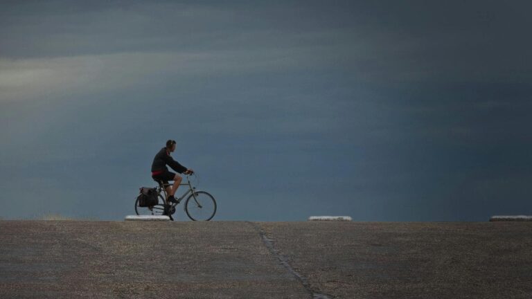 cyclist leaning into crosswind while maintaining balance and control during windy road ride
