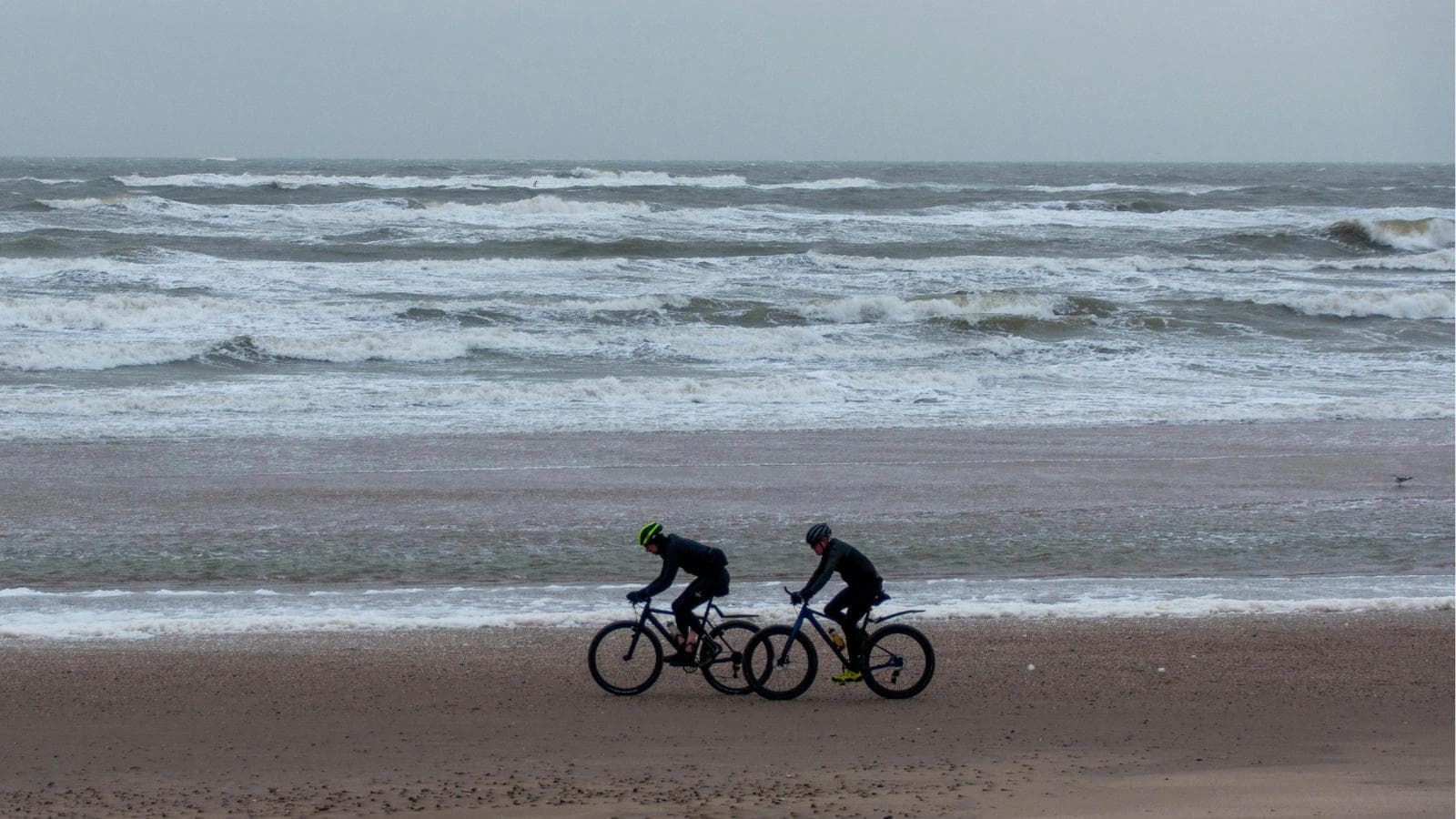 cyclist riding into strong headwind maintaining aerodynamic position and steady effort on road bike
