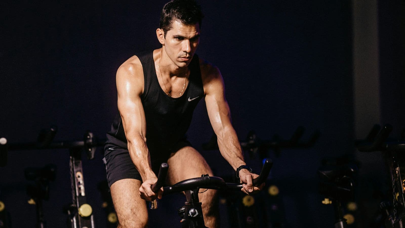Athlete training indoors on a smart trainer showing FTP cycling metrics on screen