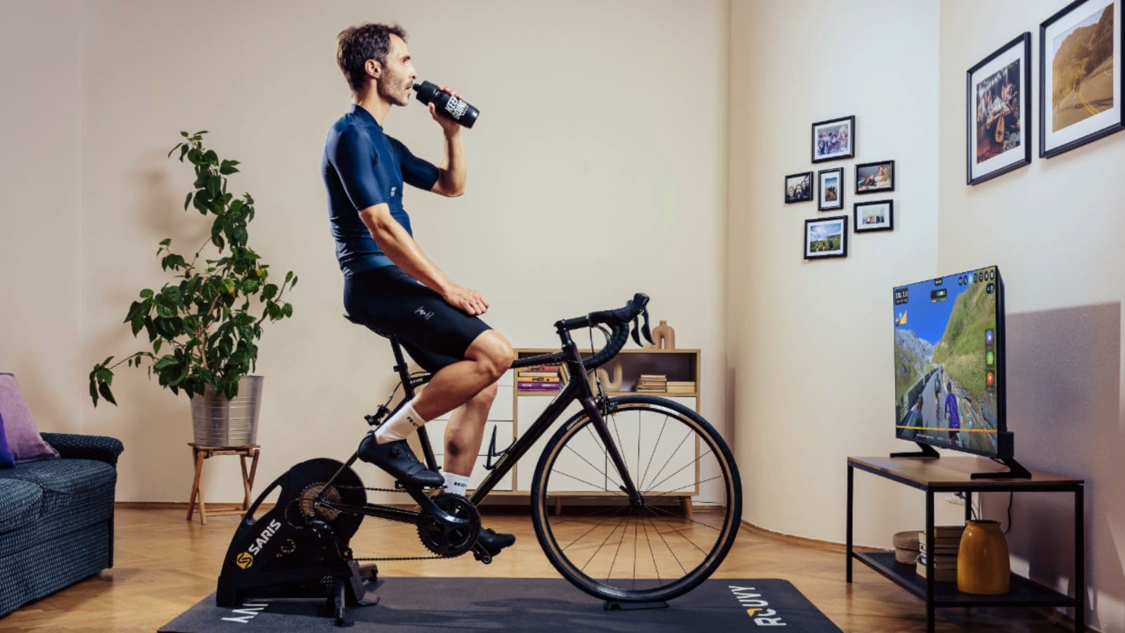cyclist drinking from water bottle during indoor cycling workout while using smart trainer