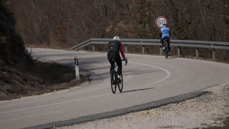 Road cyclist descending a winding mountain road with a stable body position and controlled speed.