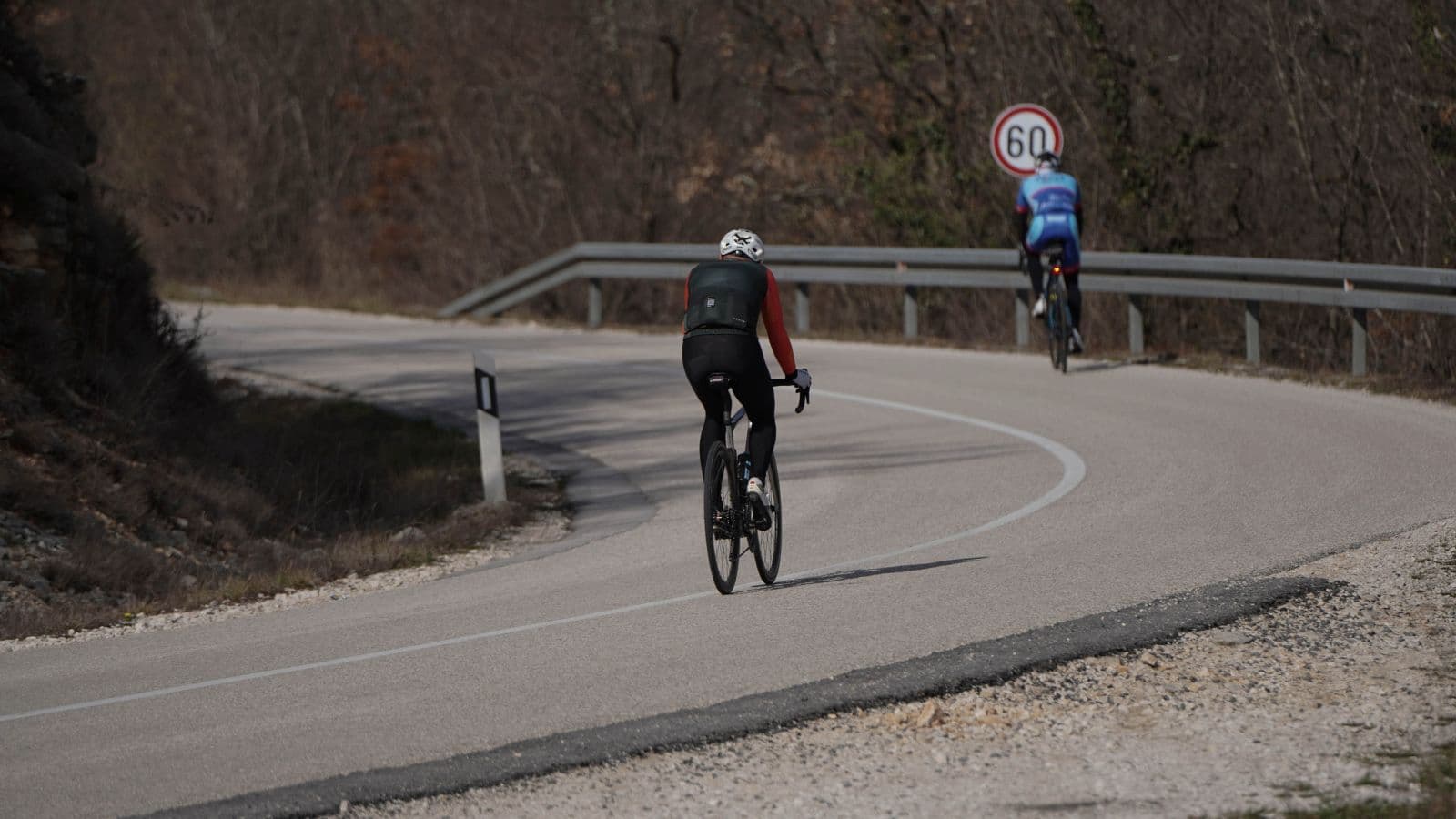 Road cyclist descending a winding mountain road with a stable body position and controlled speed.