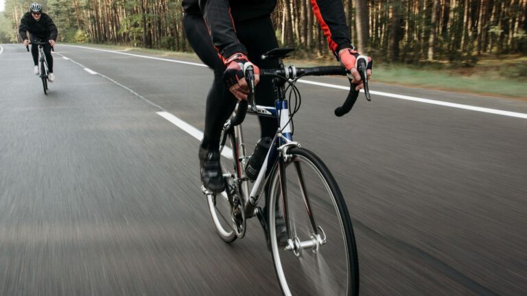 Road cyclist checking handlebar reach and riding position while adjusting a bike for improved comfort and control.