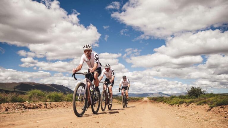Gravel cyclist inspecting tyre pressure, drivetrain, and brakes before a gravel race to ensure the bike is race-ready.