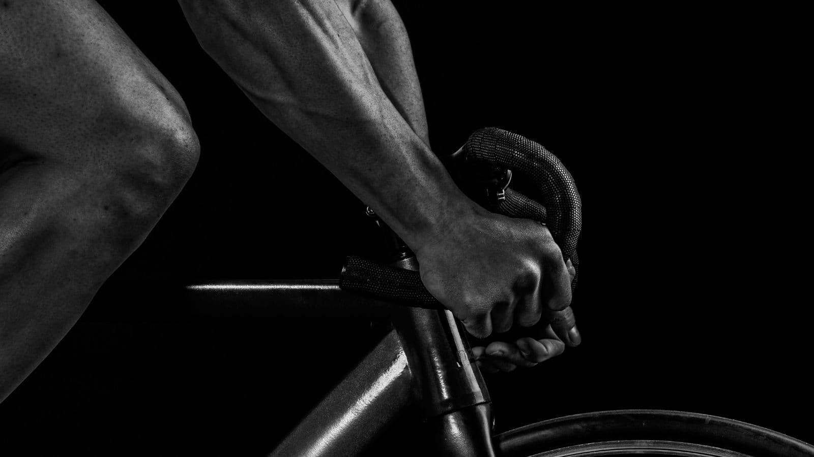 cyclist on indoor trainer with water bottles and sports nutrition during structured cycling workout